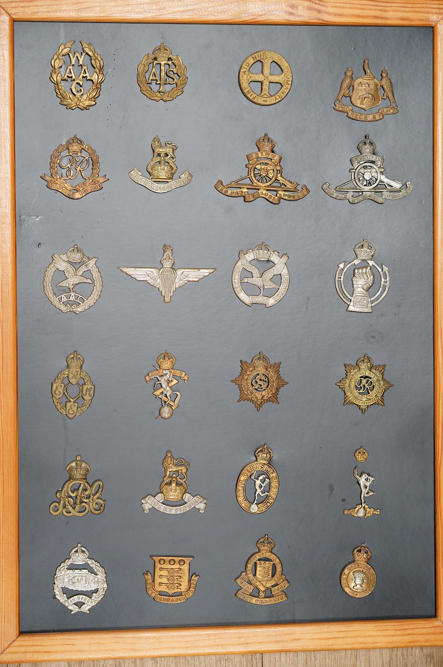A collection of ninety-five military cap badges mounted on four boards including; The Reconnaissance Corps, RAEC, Royal Engineers, Small Arms School, Royal Warwickshire 1st Birmingham Battalion, Royal Army Medical Corps,